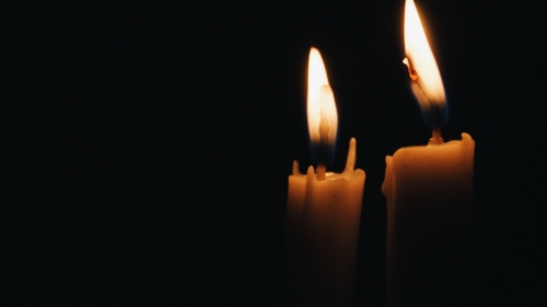 Photo of two lit candles in a dark room.