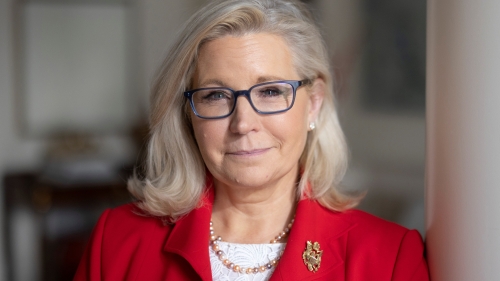 A headshot of Liz Cheney. She is wearing a red suit jacket.