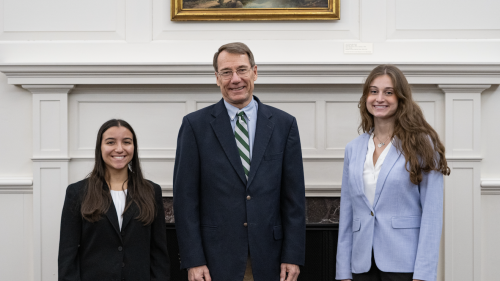 Judge with two students in front of a fireplace.
