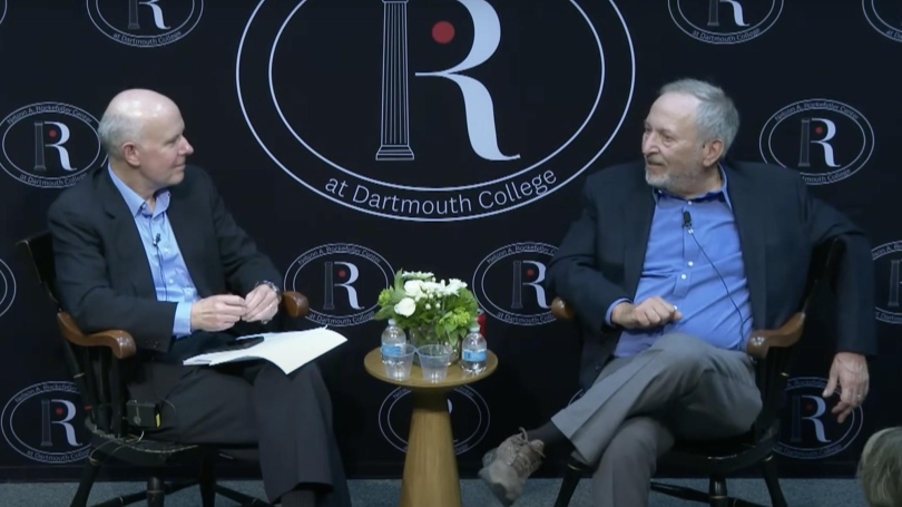 Larry Summers and Doug Irwin sit in front of a Rockefeller Center branded background.