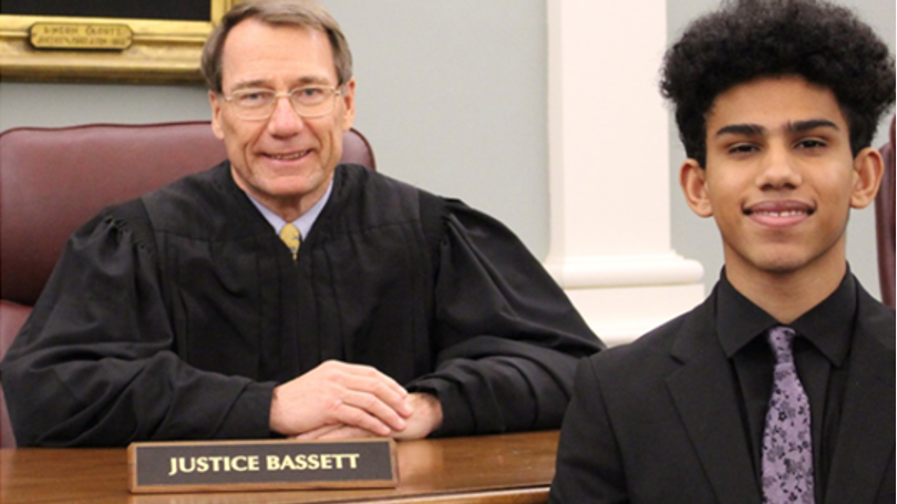 Justice Bassett sitting at his bench in robes with student Devontae Lacasse