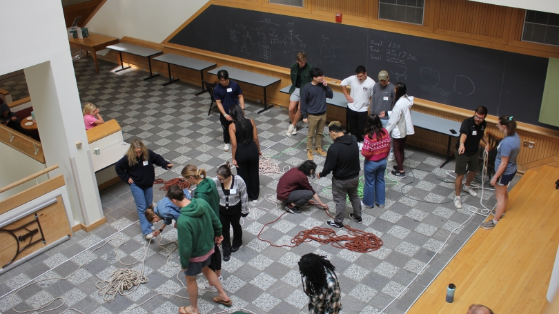 A group of students are standing and completing an activity using ropes.