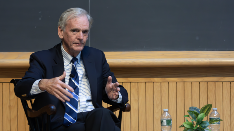 Judd Gregg sits in a chair in Hinman Forum at the Rockefeller Center.