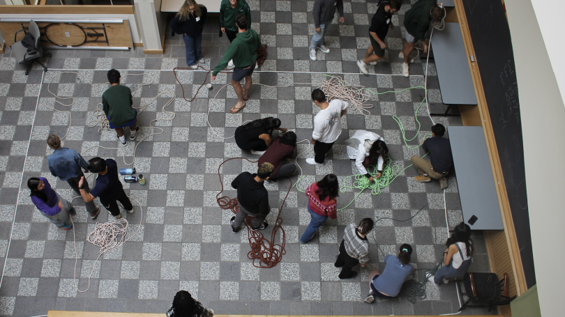 Looking down at Hinman Forum where students are working on a group activity with ropes.