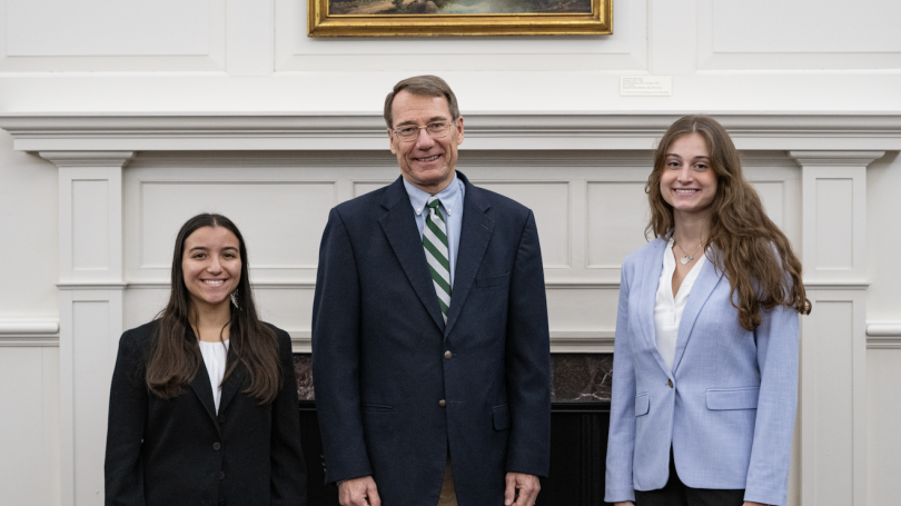 Judge with two students in front of a fireplace.