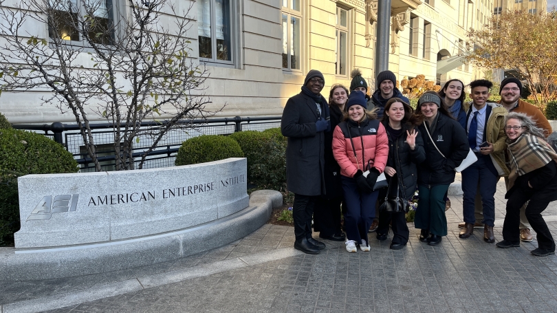 Students stand in front of the sign of the AEI 