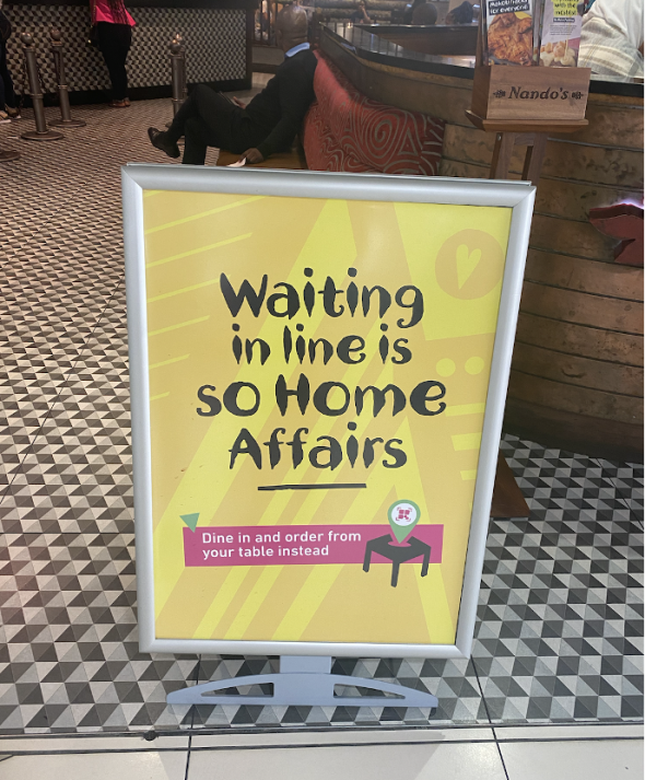 Nando's sign that reads: Waiting in line is so Home Affairs