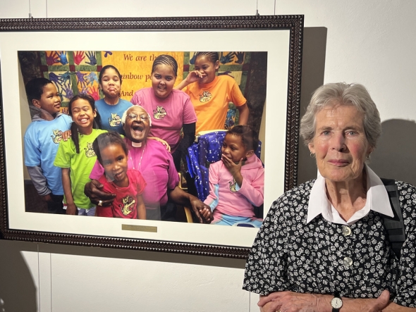 Mary Burton next to picture of Desmond Tutu and children. 