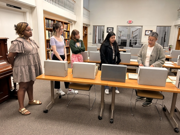 Several students look at archived materials on a table.