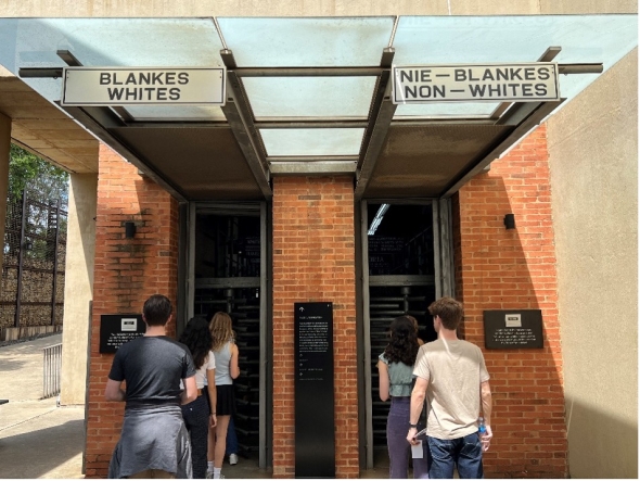 Students walk into the museum. There are two doors, one designated White and one, non-white
