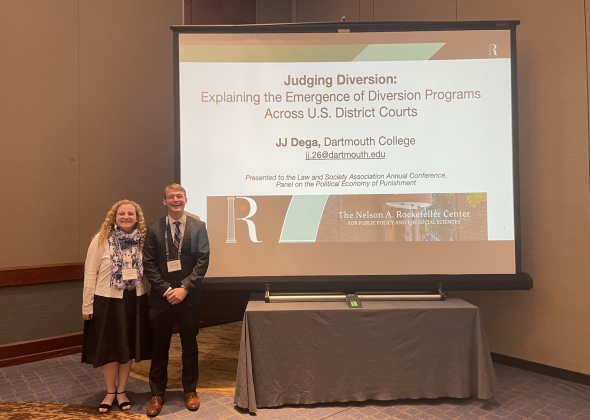 JJ Dega and Elle Pfeffer stand in front of a screen with the slide for JJ's presentation "Judging Diversion."