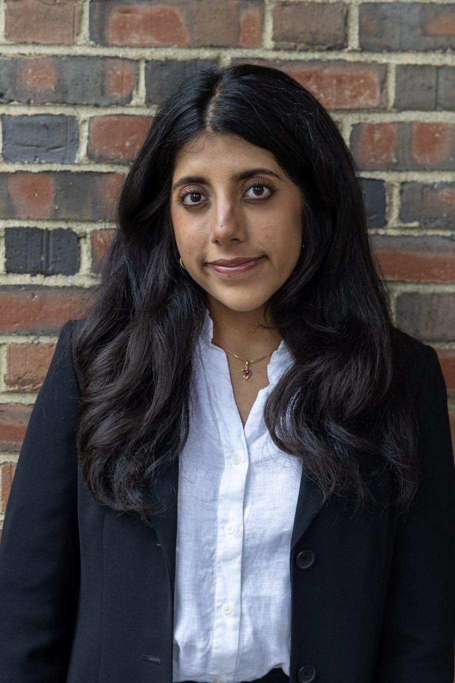 Alisha standing against a brick wall.