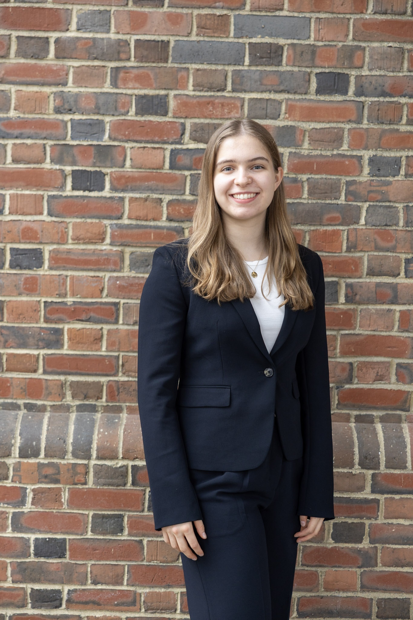 Isabel standing against a brick wall.