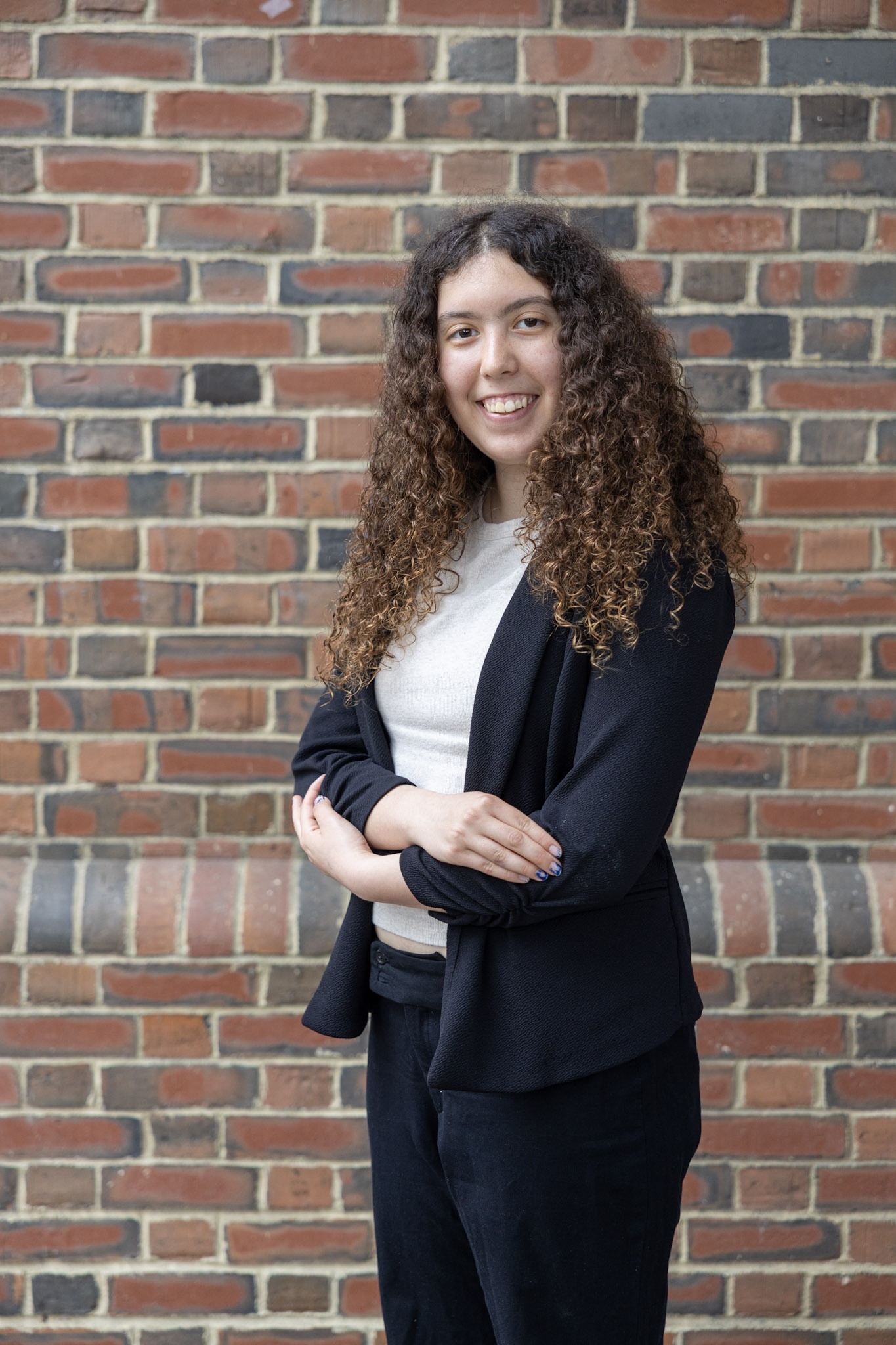 Maddy standing against a brick wall.