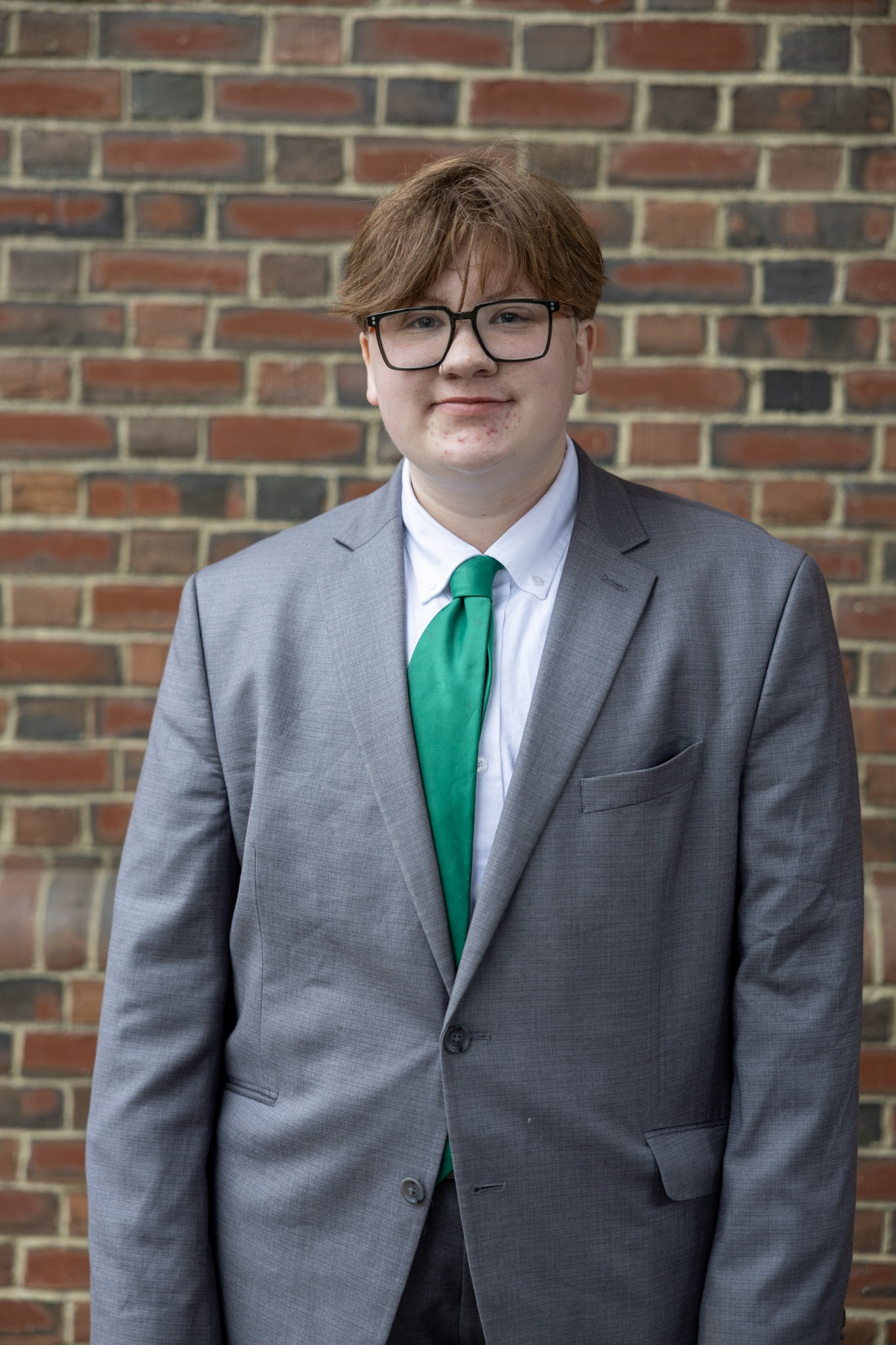 Taite standing against a brick wall.