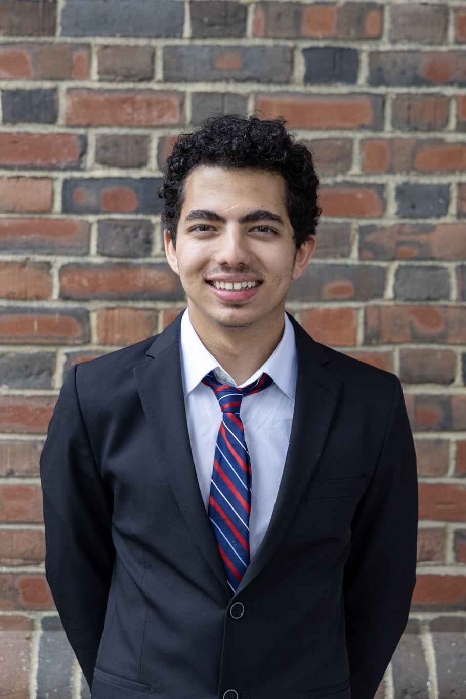 Yazid standing against a brick wall.