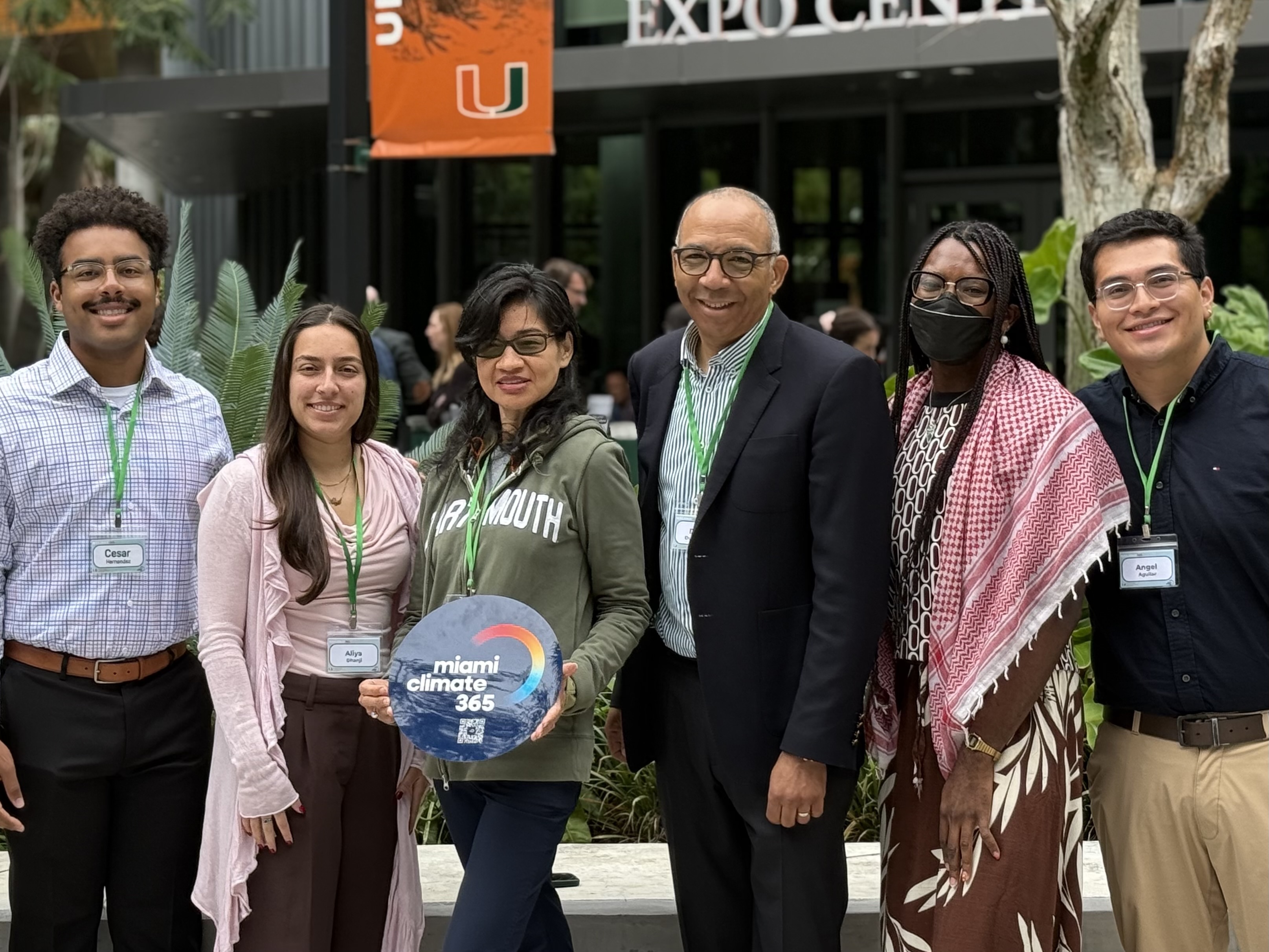 Cesar Hernandez, Aliya Dhanji, Gina Lam, David Duckenfield, Z Spicer, and Angel Aguilar stand outside. Gina is holding a Miami 365 sign.